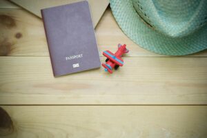 Home Flat lay of a passport, straw hat, and toy airplane on a wooden surface.