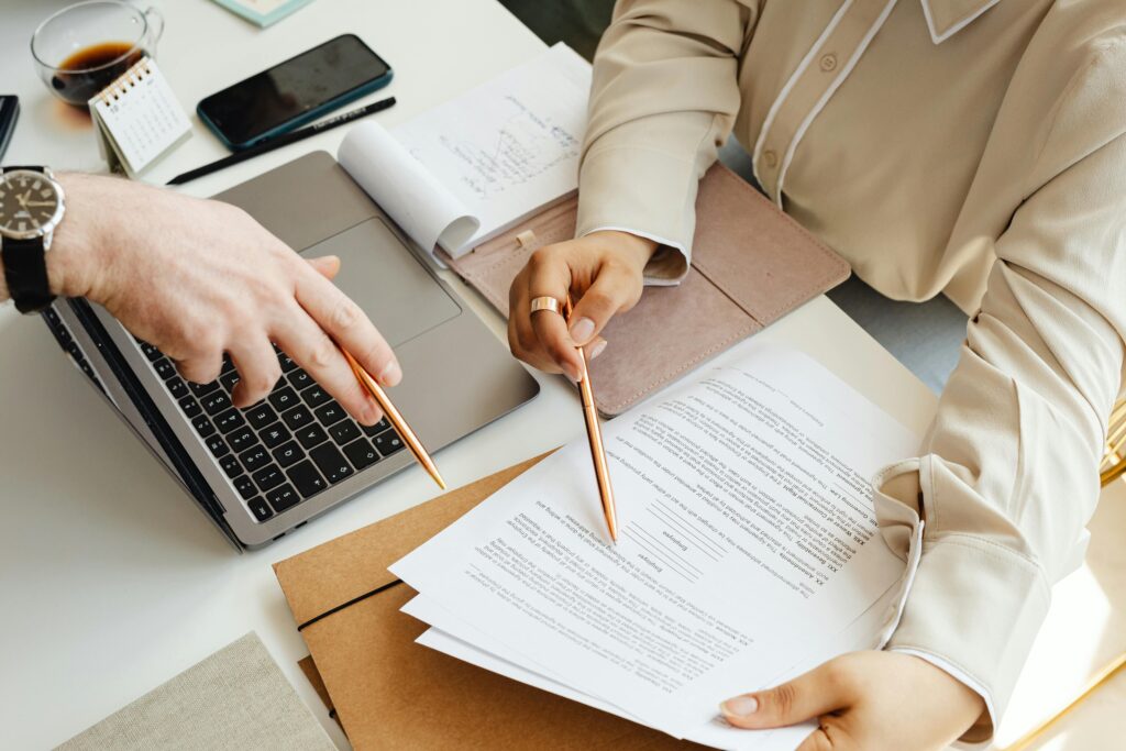 Home Office teamwork with two people reviewing documents and using a laptop